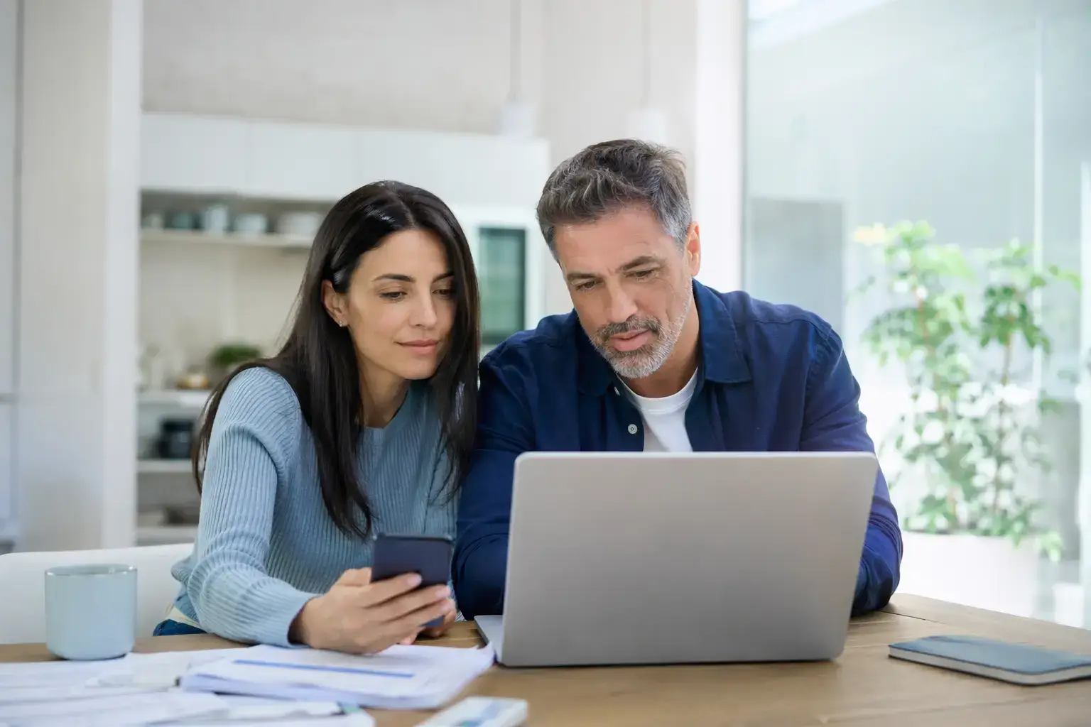 זוג בוחן נתוני משכנתא ומסמכים מול מחשב נייד בסביבה ביתית מוארת, להמחשת שירות מחזור משכנתא של אלוני פיין